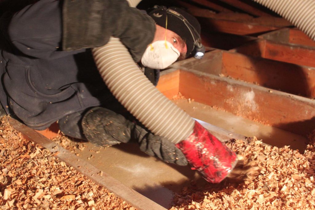Worker installing insulation into attic.