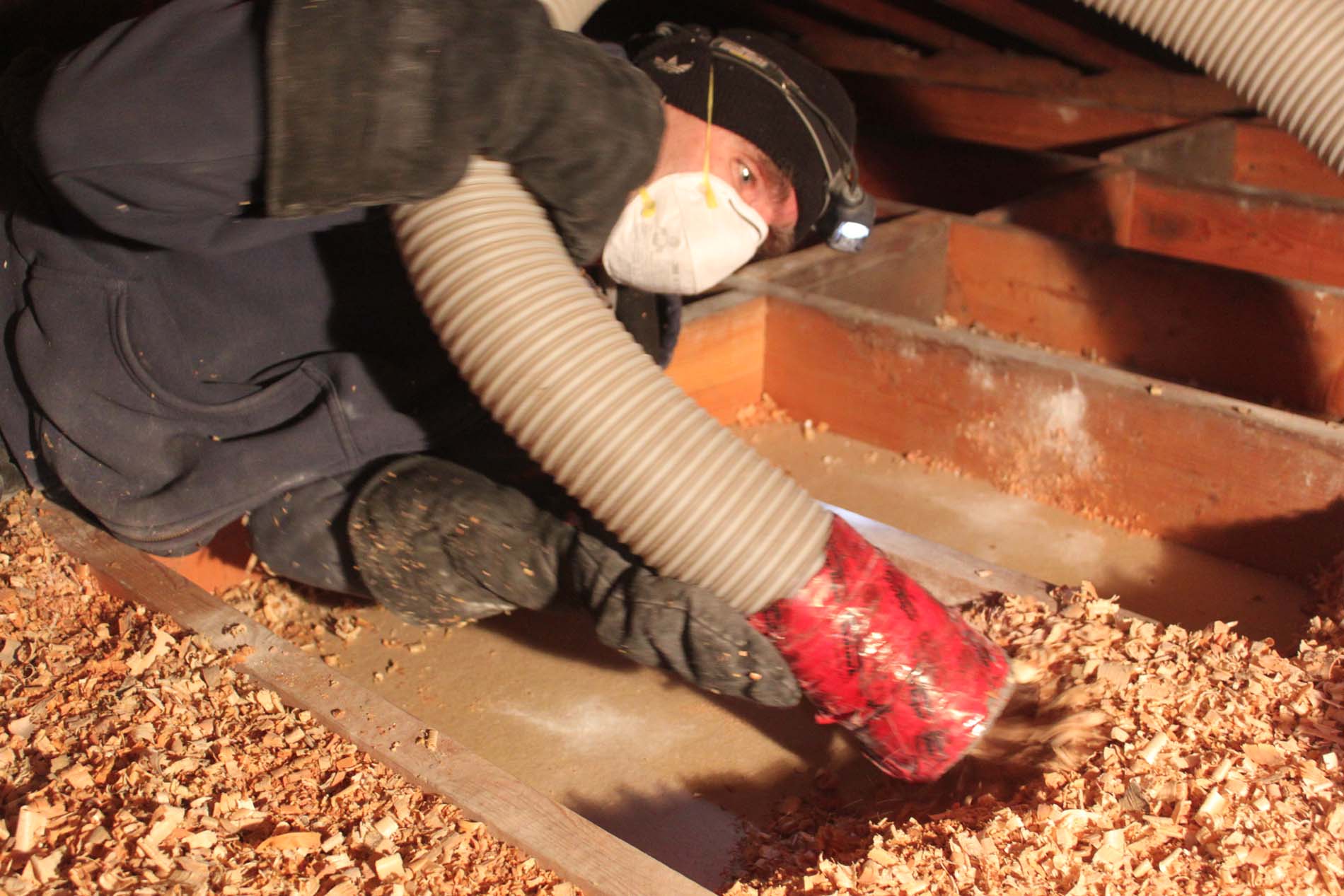 Worker installing insulation in attic.