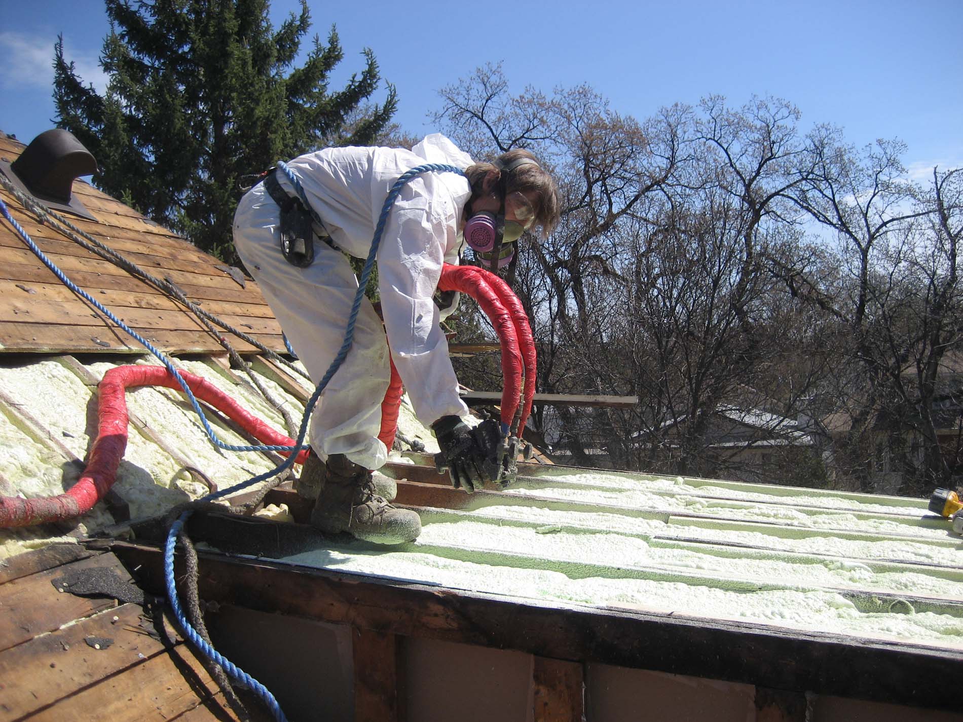 Worker spraying insulation in roof.