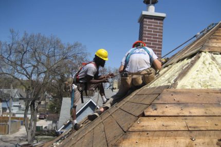 Roofers working on the side of a home.