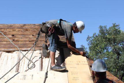 Roofer marking measurements on a wood panel.