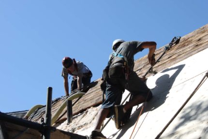 Workers installing new wood panels to roof.