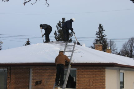 Workers removing snow from roof.