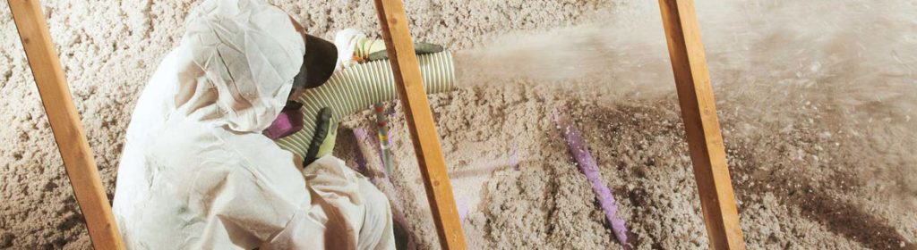 Worker spraying cellulose insulation in attic.