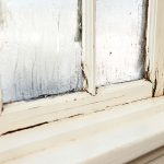 Peeling paint and condensation on a window frame.