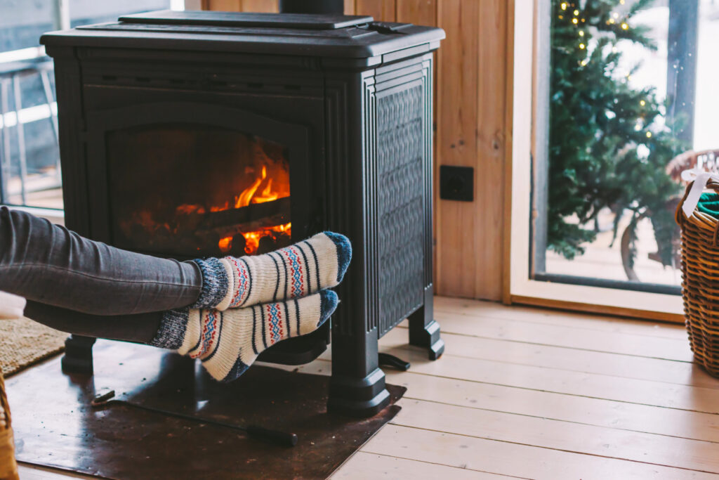 With the floor cold, feet are trying to warm up by a fire place.
