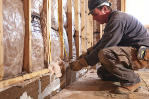 Insulation expert installing insulation in a residential home basement.
