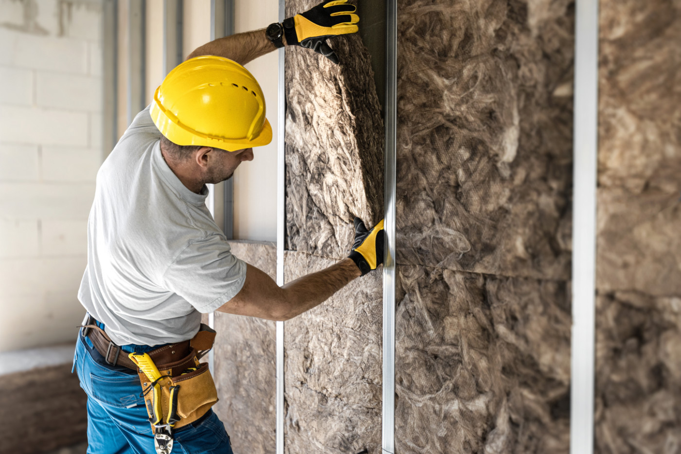 Drywaller installing accoustic insulation panels.